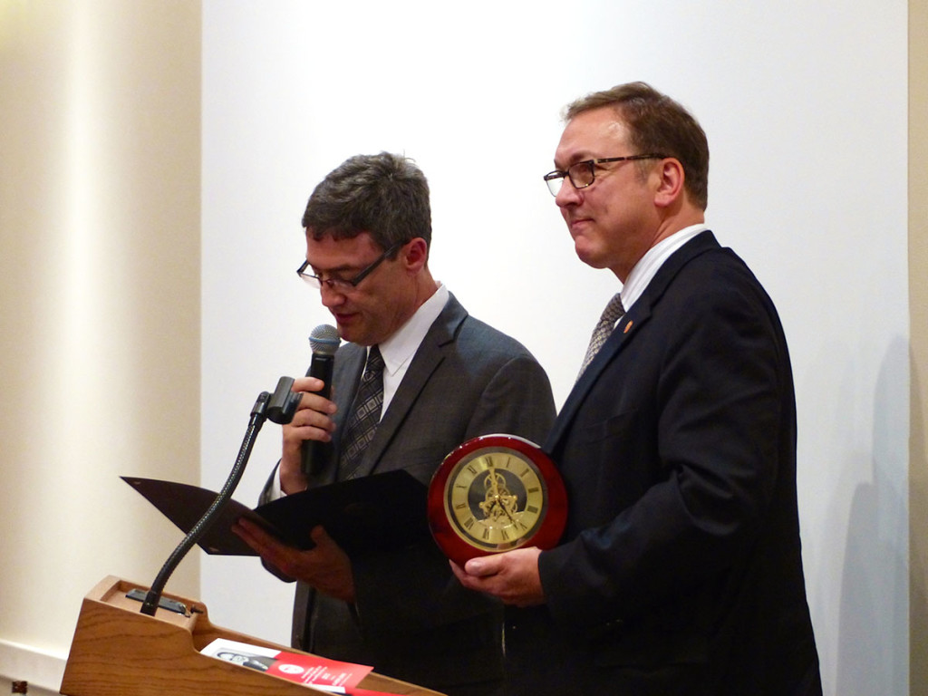 Illinois Federation of Teachers President Dan Montgomery, right, hold the traditional Person of the Year gift from the Northeastern Illinois Federation of Labor, AFL-CIO - a Michael the Archangel clock, which he will give to Karen Lewis. Northeastern Illinois Federation of Labor, AFL-CIO President Patrick Statter, left, reads an Illinois Senate recognition certificate offered by Senator Melinda Bush, citing Lewis’ dedication and fight for labor. 